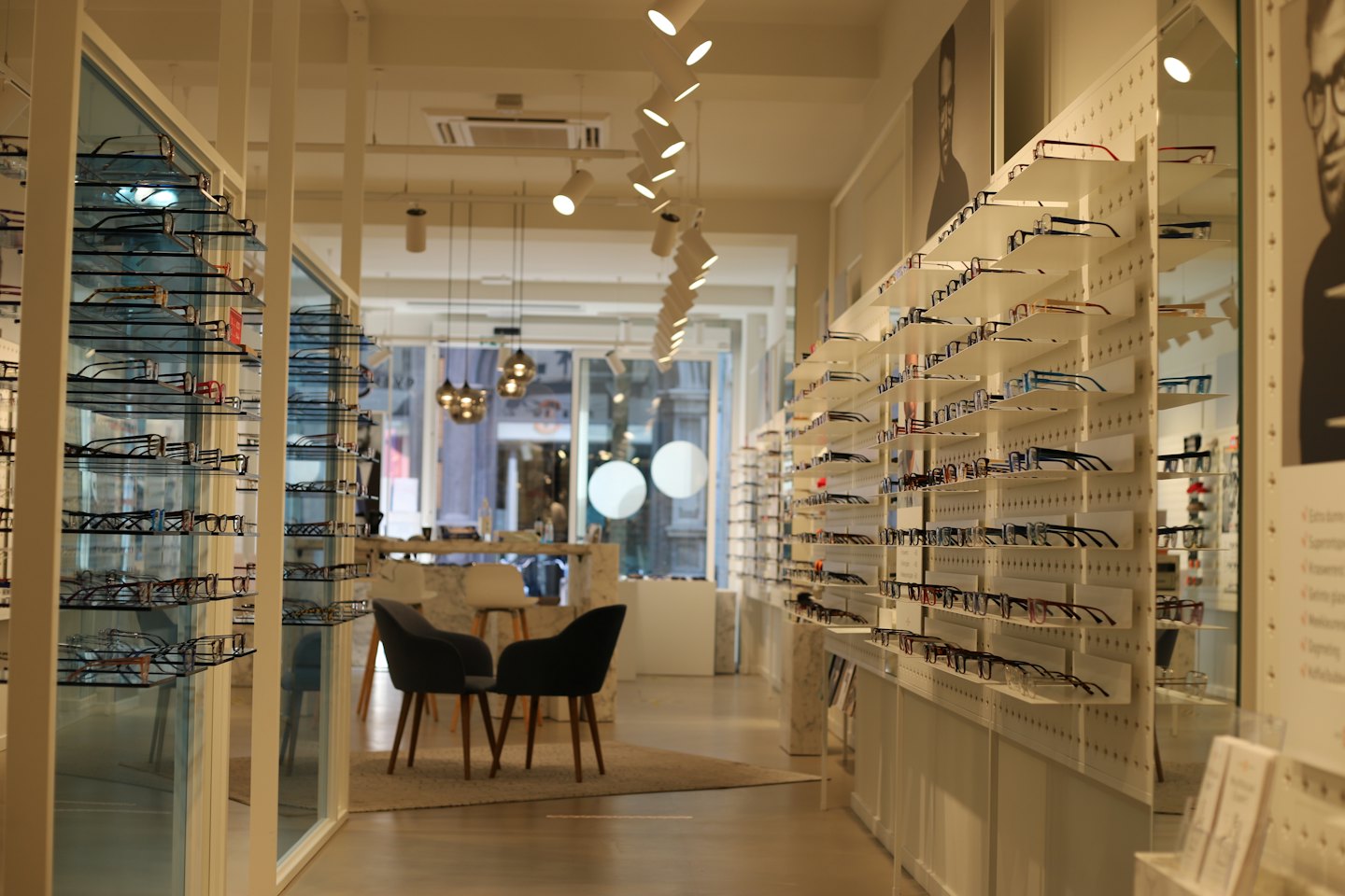 Moderner Optikerladen mit Brillen auf Regalen und Stühlen.